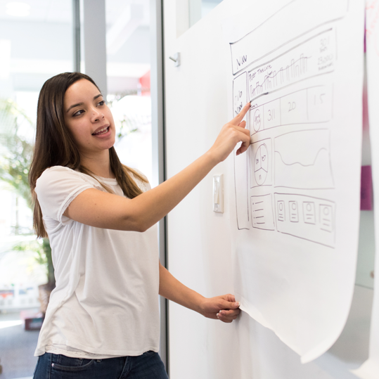 a woman pointing at a whiteboard